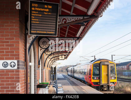 East Midlands treni permanente del treno in corrispondenza della piattaforma 4 e la scheda di partenze che mostra l'orario di partenza, Grantham stazione ferroviaria, Grantham, England, Regno Unito Foto Stock