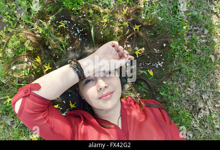 Ritratto di giovane donna, posa sull'erba e fiori di primavera Foto Stock