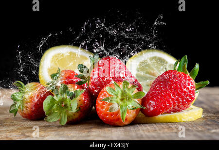 Fragole fresche su sfondo nero sul tavolo di legno Foto Stock