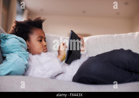 Ragazza giovane con tavoletta digitale in casa Foto Stock