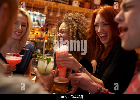 Gruppo di amici riuniti per un drink serale nel Cocktail Bar Foto Stock