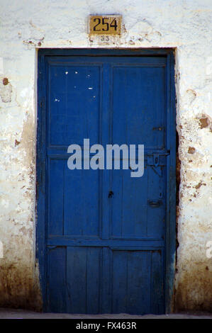 Un rustico porta blu in una parete di pelati Foto Stock
