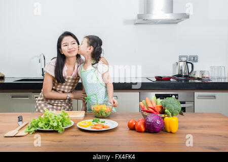 Famiglia i bambini e le persone felici concetto - Asian madre e figlia di capretto la cucina in cucina a casa Foto Stock