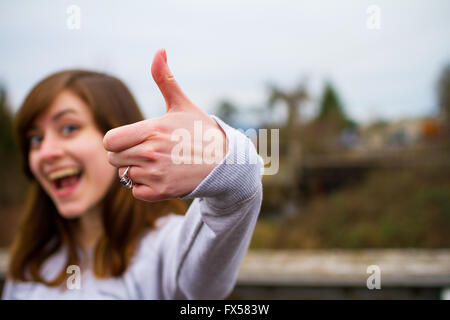 Bella ragazza facendo un pollice in alto segno con la mano e le dita per questa unica immagine di approvazione. Foto Stock