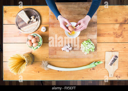 La preparazione di carbonara la pasta. Mani femminili rompere un uovo. Foto Stock