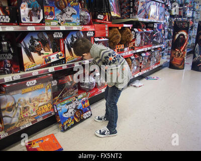 Ragazzo che guarda a Star Wars giocattoli in un negozio di giocattoli Foto Stock