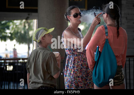 Il fumo passivo. Madre di fumare e sigaretta e soffiare del fumo nella bambino del viso. Foto Stock
