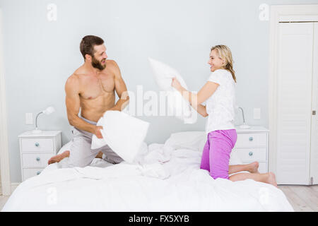 Coppia avente un cuscino lotta nel letto Foto Stock