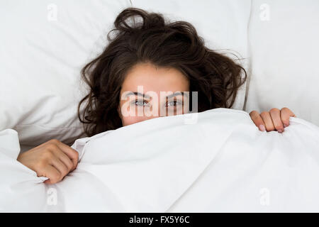 La donna che si nasconde sotto una coperta per letto Foto Stock