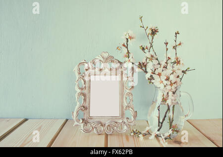 Vintage telaio vuoto accanto al bianco fiori di primavera. messa a fuoco selettiva. modello, pronti a mettere la fotografia. vintage filtrata Foto Stock