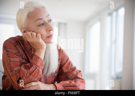 Caucasian donna seduta con mento in mano Foto Stock