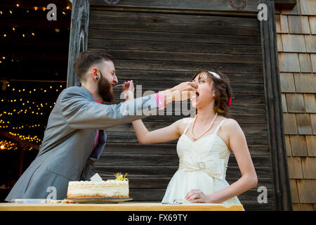 Sposa e lo sposo tagliare la torta e feed ogni altro il giorno delle nozze presso la reception. Foto Stock