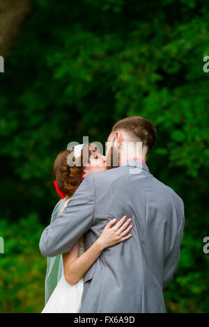 Primo bacio come marito e moglie questa sposa e lo sposo abbracciare durante il momento della loro cerimonia nuziale. Foto Stock