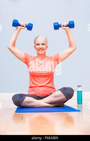 La donna caucasica sollevamento pesi sul materassino yoga Foto Stock