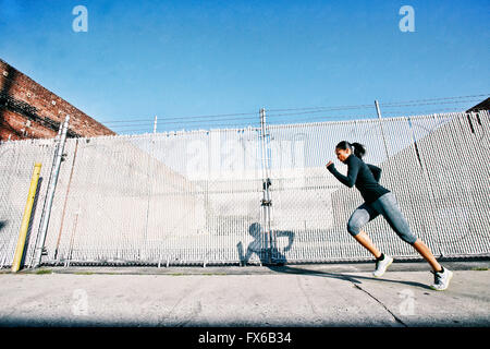Razza mista donna jogging sul marciapiede Foto Stock