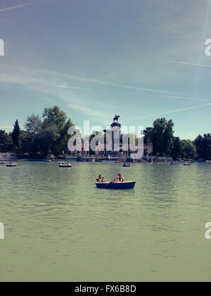 Le persone sono barche di equitazione su un lago artificiale nella parte anteriore del re Alfonso XII monumento di El Retiro Park in Madrid Foto Stock