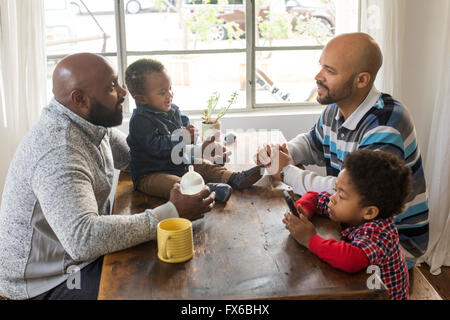 I padri e i bambini seduti a tavola Foto Stock