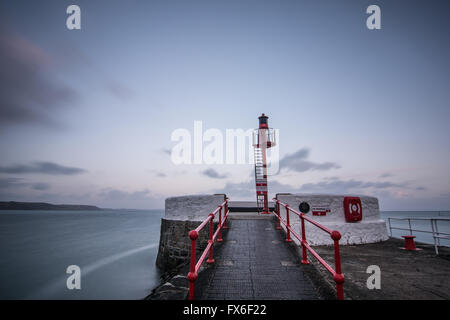 Tramonto con esecuzione di nuvole sopra il molo nel villaggio di Looe, sud della Cornovaglia, Inghilterra Foto Stock