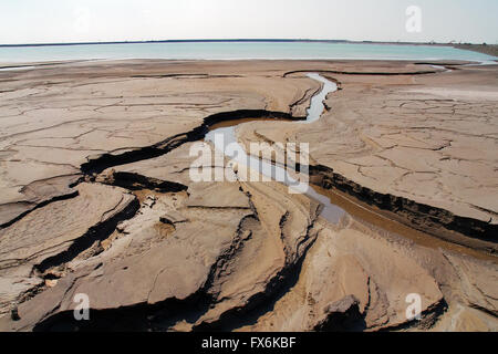 Erosione dei terreni con canali a rifiuti industriali e la zona industriale di acqua serbatoio aperto in background Foto Stock