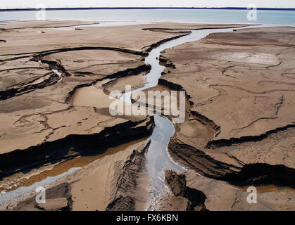 Erosione dei terreni con canali a rifiuti industriali e la zona industriale di acqua serbatoio aperto in background Foto Stock