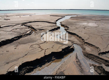 Erosione dei terreni con canali a rifiuti industriali e la zona industriale di acqua serbatoio aperto in background Foto Stock