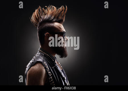 Colpo di profilo di una giovane punk rocker con un Mohawk acconciatura su sfondo scuro Foto Stock