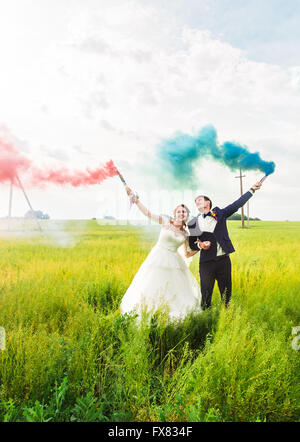 La sposa e lo sposo con il fumo delle bombe sul prato Foto Stock