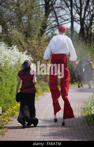 Uomo con i capelli rossi e pantaloni camminando su palafitte in posizione di parcheggio con il gotico vestito ragazza al suo fianco in abiti d'epoca, originale unico giovane Foto Stock
