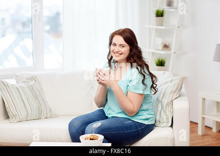 Felice Taglie donna con coppa e biscotti a casa Foto Stock