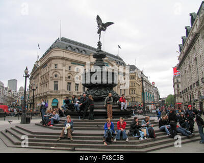 Turisti che si siedono sui gradini della struttura Shaftesbury Memorial Fountain a Piccadilly Circus. Foto Stock