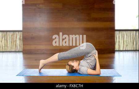 Donna fare yoga in aratro pone sul tappeto Foto Stock