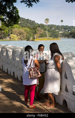 Sri Lanka, Kandy, Dalada Vidiya, donna chiacchierando accanto a Kiri Muhuda Lago Foto Stock