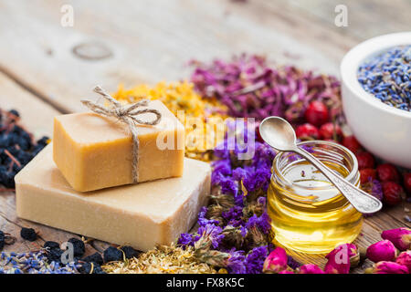 Barre di saponi fatti in casa, miele o olio, cumuli di erbe curative e di mortaio di lavanda. messa a fuoco selettiva. Foto Stock