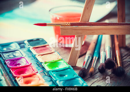 Serie di acquerelli di vernici e paintrushes per la verniciatura di primo piano. Messa a fuoco selettiva. In stile retrò. Foto Stock