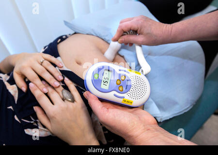 La levatrice ascoltando una donna incinta del battito cardiaco del bambino  con un doppler monitor fetale Foto stock - Alamy