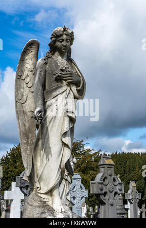 Un angelo santo statua si trova al di sopra di tombe nel cimitero di Glasnevin a Dublino Foto Stock