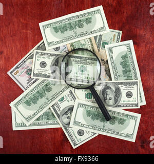 Lente di ingrandimento posta sul centro di denaro dollaro e sfondo legno, concetto di business Foto Stock