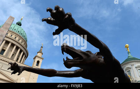 Potsdam, Germania. Xiii Apr, 2016. Il raggiungimento fuori artiglio del uno 63 sculture intitolata 'Wolfsmenschen' (lit. Wolf persone) dall artista Rainer Opolka sono sul display davanti alla storica chiesa di San Nicola (l) e il vecchio municipio presso la Alte Markt square a Potsdam, Germania, 13 aprile 2016. " Il pacco di lupi stand simbolicamente per 'odio la gente, tubi espulsori di arson, Neonazis, adirato contro i sostenitori di Pegida AfD e che vogliono sparare ai rifugiati', Opolka ha spiegato le sue opere d'arte. Le sue sculture sono state precedentemente sul display alla chiesa Frauenkirche di Dresda. Foto: Ralf Hirschberger/dpa/Alamy Live News Foto Stock