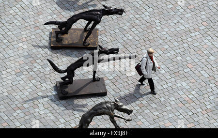 Potsdam, Germania. Xiii Apr, 2016. Una passeggiate a piedi dopo una fila di 63 sculture intitolata 'Wolfsmenschen' (lit. Wolf persone) dall artista Rainer Opolka presso la Alte Markt square a Potsdam, Germania, 13 aprile 2016. " Il pacco di lupi stand simbolicamente per 'odio la gente, tubi espulsori di arson, Neonazis, adirato contro i sostenitori di Pegida AfD e che vogliono sparare ai rifugiati', Opolka ha spiegato le sue opere d'arte. Le sue sculture sono state precedentemente sul display alla chiesa Frauenkirche di Dresda. Foto: Ralf Hirschberger/dpa/Alamy Live News Foto Stock