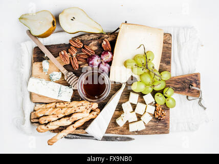 Antipasto di formaggio di set. Vari tipi di formaggi, miele, uva, pera, dadi e pane grissini rustico di legno su w Foto Stock