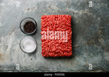 Carni macinate forcemeat su pietra ardesia sfondo con sale e pepe Foto Stock