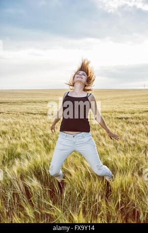 Crazy donna caucasica è il salto nel campo di grano e rende grande divertimento. La bellezza e la natura. Foto Stock