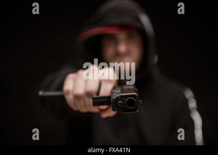 Un giovane punti penale una pistola semi-automatica con un caricatore esteso al visualizzatore. Foto Stock