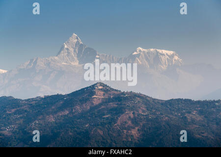 I vertici di Annapurna III e Machapuchare nella foschia dietro il monte Sarangkot ridge, Thumki, Kaski, Nepal Foto Stock
