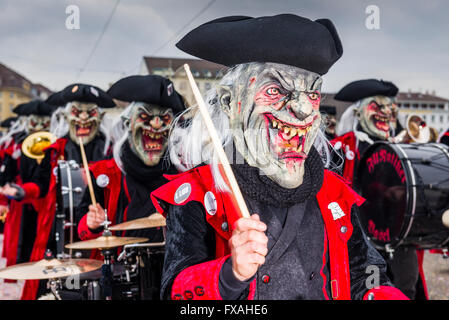 Membri della Gugge Marching Band di ottone che indossa abiti a fantasia e le maschere per la grande processione al Carnevale di Basilea Foto Stock