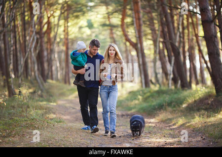 La famiglia felice con raccoon camminando in una foresta Foto Stock