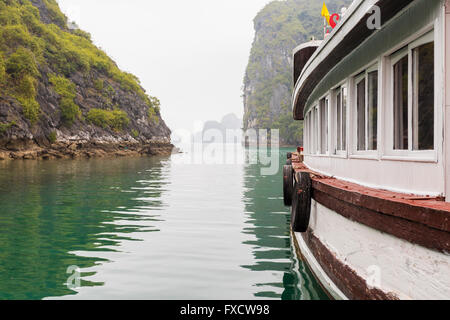 Barca bianca in un giorno nuvoloso nella Baia di Ha Long, Vietnam Foto Stock