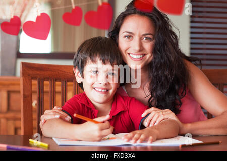 Immagine composita di felice madre aiutando il suo figlio per i compiti a casa Foto Stock