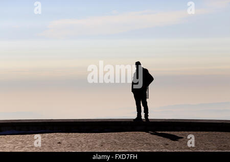 Uomo in controluce si ammira la vista dalla cima di una montagna Foto Stock