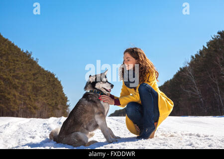 La donna gioca con il cane nella foresta di inverno Foto Stock